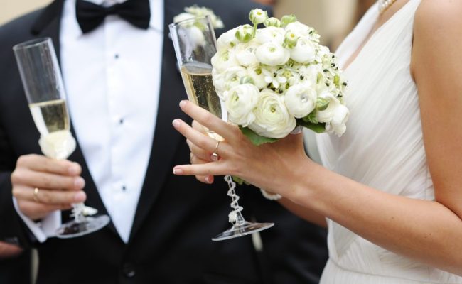 Bride and groom are holding champagne glasses